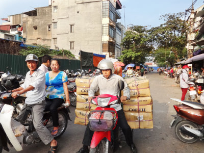 Street near the main market. Workers often carry heavy loads on their motorcycles as seen here - Hanoi, Vietnam