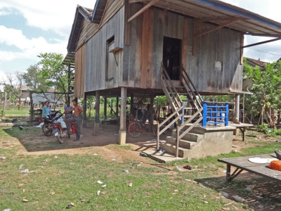 A stilted house with a few guys next to it - in the rural village where we met our sponsored girls who are high school students