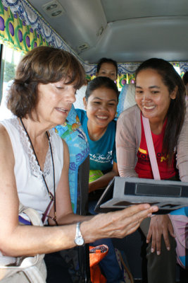 Judy showing photos of her family on her mini tablet to some of our sponsored young ladies (college students) - on our bus