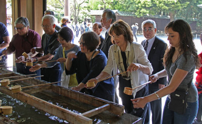 Judy and others engaging in ceremonial purification and cleansing at a temizuya before entering the main shrine at Meiji.