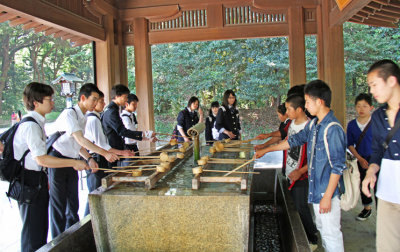 Students engaging in ceremonial purification and cleansing at a temizuya before going to the main shrine at Meiji   