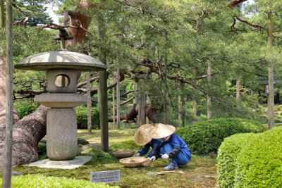 Workers near a traditional Yukimi (snow viewing) stone lantern at the Kenroku-en Garden in Kanazawa