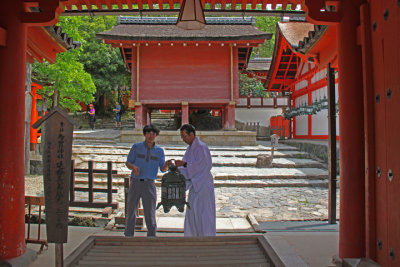A monk and his assistant hanging a bronze lantern at Kasuga Taisha (a Shinto shrine) in Nara Park in Nara