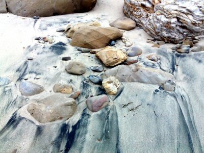 The black color in the sand is the mineral Magnetite. If the sand was dry, you could lift the black particles out with a magnet.