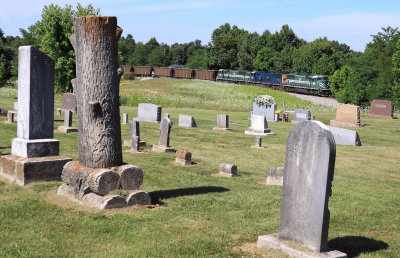 P&L train Lcl3 tops over the hill at Summit and passes a small church graveyard