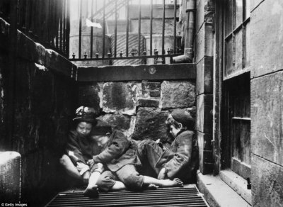 Three young street children huddle together over a grate for warmth in an alleyway off Mulberry Street Manhattan.jpg