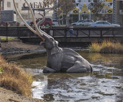 Open tar pit with prehistoric elephant sculpture