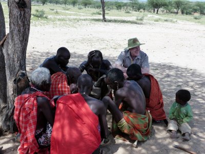 The elders play a game of mancala in the Samburu Village while Mike & the little one look on.