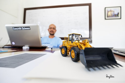SELFIE WITH AN UWA. My cluttered desk becomes my studio for an experimental selfie session to check how this zoom renders the out-of-focus busy background. 
I laid down the camera on the desk with the wide open 16-35 f4 IS, focused on the model payloader via live view (near MFD), then tripped the shutter using the self-timer.

Shooting info - Rosario, La Union, Philippines, May 28, 2015, Canon 5D MIII + EF 16-35 f/4 L IS, 16 mm, f/4, ISO 160, 1/10 sec, 
manual exposure in available light, live view AF, self-timer, AWB, uncropped full frame resized to 1500 x 1000 pixels.