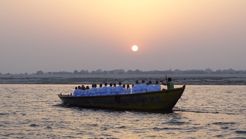 Monks in a boat enjoy sunrise on the Ganges