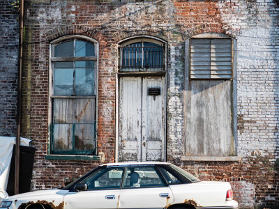 Old Building Deteriorating w Rusty Car in Foreground