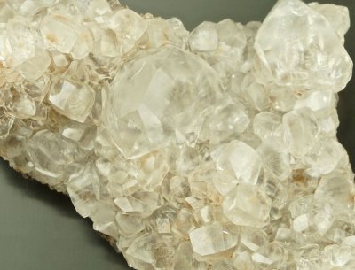 Calcite, lustrous transparent crystals to 20 mm in 75 mm group. Frizington, West Cumbria, England. The main crystal is twinned.