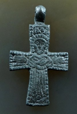 Figure with crossed arms and long dress appears on the reverse of this 10th C cross. Greek Gamma Omicron above.