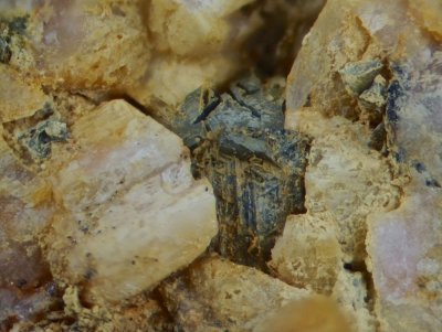 Reticulated sagenite (centre) above pyrite with strange dissolution channels and K-feldspar. Shap Granite Quarry.