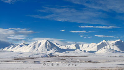 Snow covered Brooks Range mountains Alaska with blue sky from the Dalton Highway
