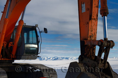 Orange excavator on the Dalton Highway in the Brooks Range with Alyeska oil pipeline Alaska