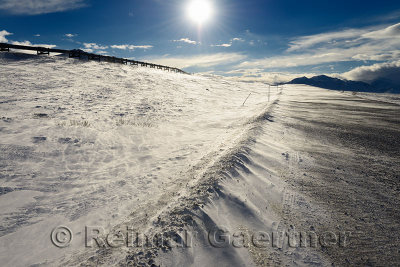 Sun and blowing snow on the Dalton Highway through the Brooks Range mountains Alaska