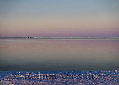 Pink sky over calm water of the Beaufort Sea at Kaktovik Alaska at sundown