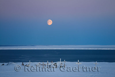 Red Moon rising over the Beaufort Sea and Kaktovik lagoon with cemetery grave markers