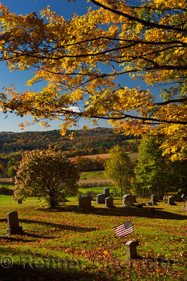 Gold maple leaves Hydrangea and American flag at Peacham Corner Cemetery Vermont in the Fall