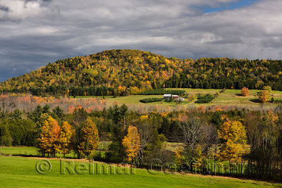 Isolated farmhouse among orange trees in Fall color under Blue Mountain Vermont