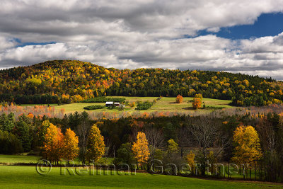 Isolated farmhouse among forest trees in Fall color on Blue Mountain Vermont