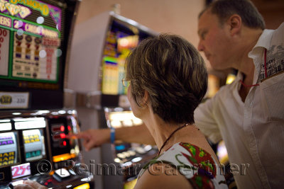 Man explaining readout to a woman on slot machines in a casino