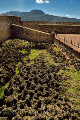 Fort St Philip with lava rock moat and Isabel de Torres mountain Puerto Plata Dominican Republic