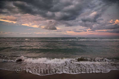 Dark pink clouds at sunset with coral reef waves on beach of Maimon Bay Dominican Republic