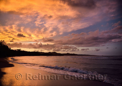 Golden clouds at sunset reflecting off wet beach sand Maimon Bay Dominican Republic