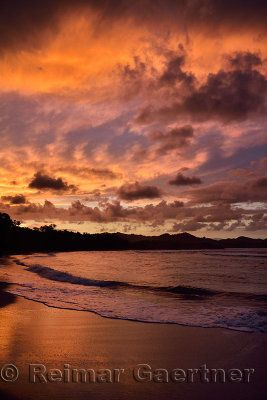 Red clouds at sunset reflecting off wet beach sand Maimon Bay Dominican Republic