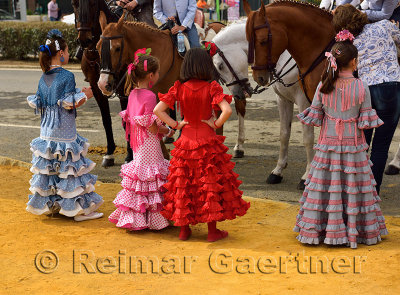 Young girls in flamenco dresses looking at horses at the April Fair in Seville Spain