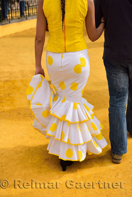 Woman in yellow flamenco dress at the Seville April Fair walking on ochre earth mined in Alcala de Guadaira