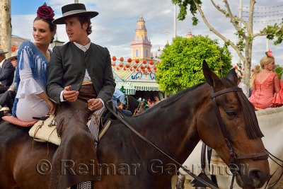 Handsome man and Beautiful woman drinking on horseback with 2015 Main Gate of the Seville April Fair