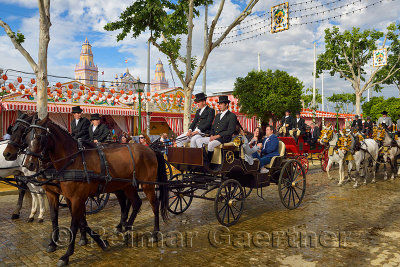 Men dressed in traje corto suits driving teams of horses pulling carriages at Seville April Fair with temproary Casetas and Main