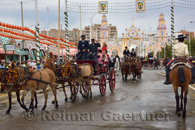 Horse and mule drawn carriages and riders on Antonio Bienvenida street with Main Gate 2015 Seville April Fair