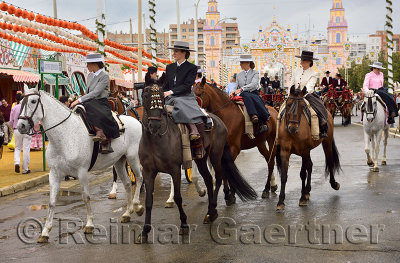 Women on horseback riding sidesaddle on Antonio Bienvenida street with Main Gate 2015 Seville April Fair