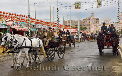 Parade of horse drawn carriages on Antonio Bienvenida street with casetas and Main Gate 2015 Seville April Fair