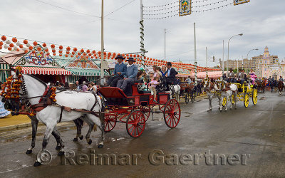 Parade of horse drawn carriages with families at the Main Gate 2015 Seville April Fair