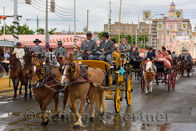 Line of horse drawn carriages with families and riders at the Main Gate 2015 Seville April Fair