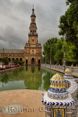 South Tower reflected in canal with painted ceramic railings at Plaza de Espana Seville Spain