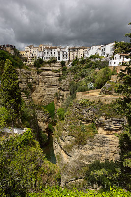 White houses and dark clouds over the Guadalevin river at the El Tajo Gorge Ronda Spain