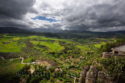 Dappled sunshine on green farm fields in valley below the mountain city of Ronda Spain