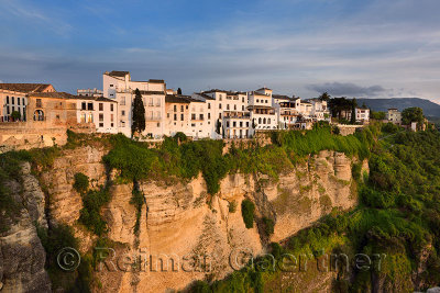 Evening sun on white buildings and orange cliffs at El Tajo Gorge Ronda Spain