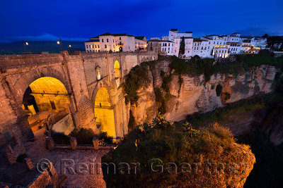 Twilight on white buildings and orange cliffs lit for the night at El Tajo Gorge Ronda Spain