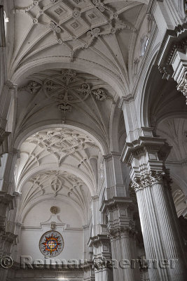 White columns and ribbed vault ceiling with stained glass window in the Granada Cathedral of the Incarnation