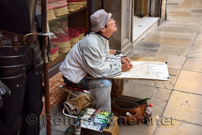 Street painter looking up at the Granada Cathedral of the Incarnation in Pasiegas Square