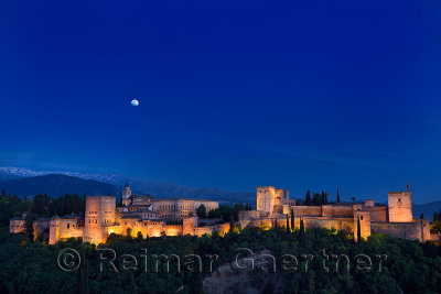 Indigo sky and moonrise over hilltop Alhambra Palace fortress complex at twilight Granada