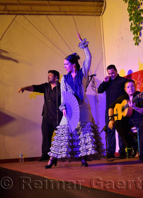 Female Flamenco tap dancer with fan on stage at night in an outdoor courtyard in Cordoba Spain