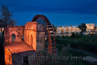 Lights on Albolafia Waterwheel at dusk on the Guadalquivir river with Roman Bridge and Calahorra Tower Cordoba